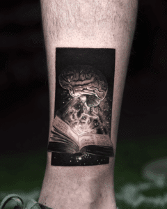 Tattoo design featuring an open book with a brain above it, surrounded by cosmic elements, showcasing black and grey realism, reflecting Pony Lawson's artistic style and creative influences.